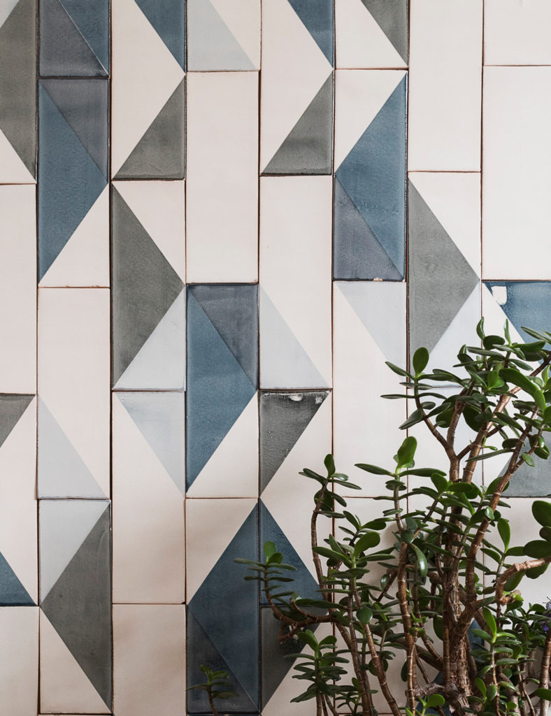 Smink Studio Going Overground tiles with screen-printed triangles in blue, grey and white beside a jade plant.