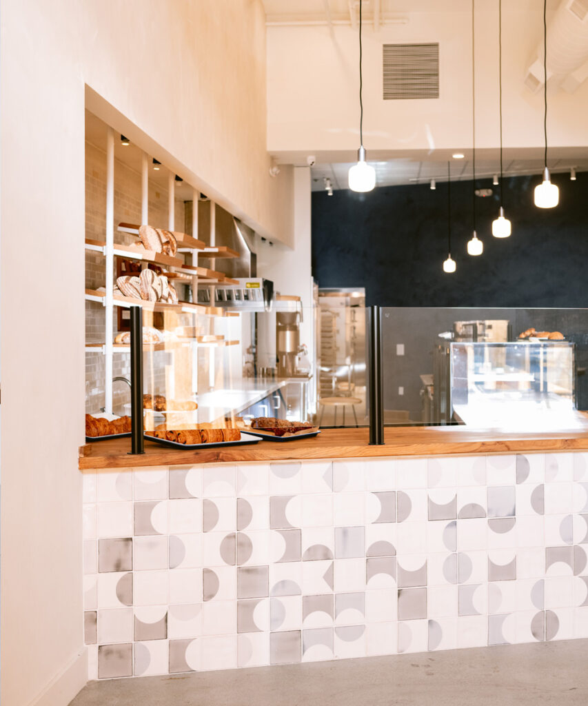Starter Bakery interior by Caha Design, its counter faced with grey and white Smink Studio screen-printed tiles.