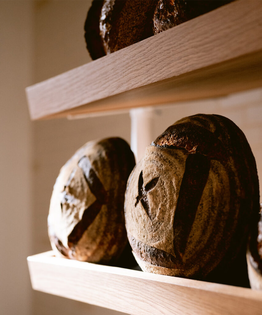 Sourdough loaves on oak shelves at Starter Bakery.