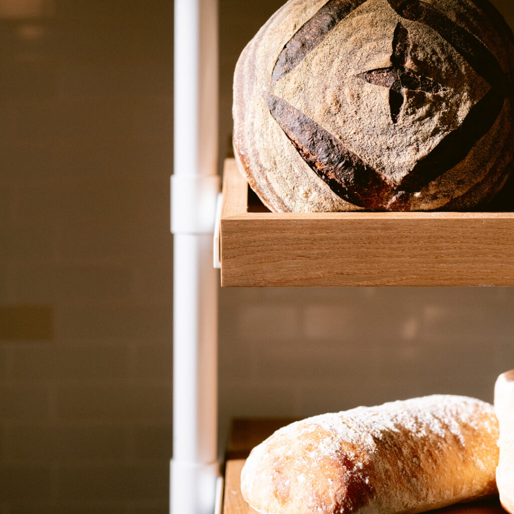 Scored sourdough loaves on wooden shelves at Starter Bakery.