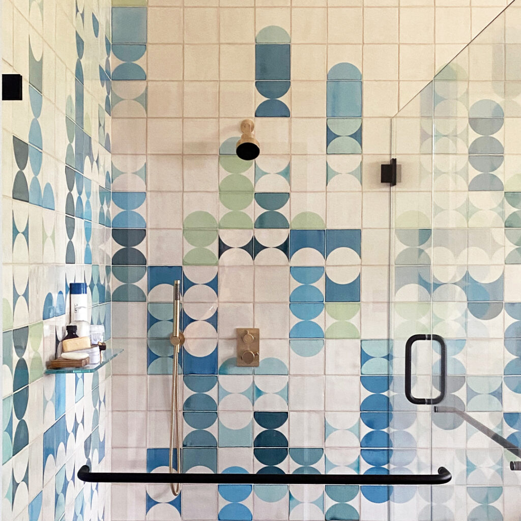 Walk-in shower with black fittings, lined with Smink Studio Bubblebath tiles in blue, teal and sage screen-printed half-circles.