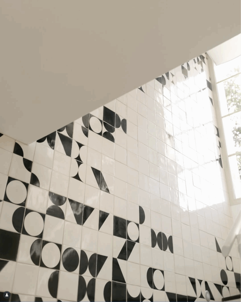 Stairwell seen from below, with white Smink Studio handmade tiles bearing black screen-printed geometric shapes, for Imraum Design.