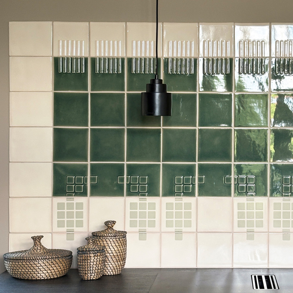 Kitchen wall of white and bottle-green Smink Studio Building Blocks tiles with screen-printed square motifs and a black pendant.