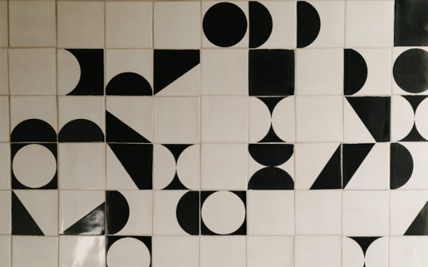 Wall of white Smink Studio handmade tiles with bold black screen-printed half-circles, circles and triangles.