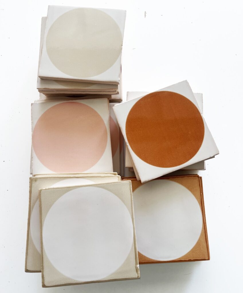 Stack of Smink Studio handmade tiles with screen-printed circles in cream, blush, burnt orange and white glazes.