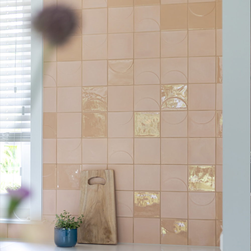 Kitchen corner of blush-pink Smink Studio handmade ceramic tiles with tonal half-circle screen-printed colours and glossy metallic-lustre accents.