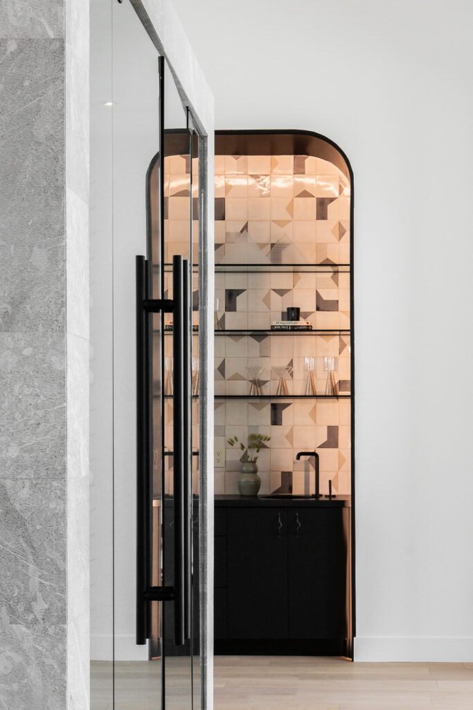 Hallway leading to an arched niche bar lined with blush and terracotta Smink Studio handmade ceramic tiles in geometric cube screen-printed colours.