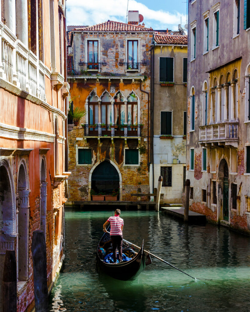 Gondolier on a narrow Venice canal lined with weathered palazzi, the setting of the Smink Studio Biennale tile project.