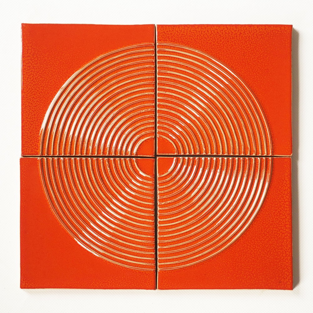 Four Smink Studio Relief tiles in a glossy orange-red glaze, laid together so the concentric Ley lines rings form one complete circle.