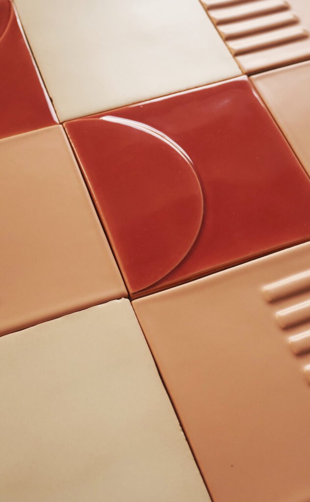 Close-up of Smink Studio Relief tiles in deep red and blush pink, combining a raised half-circle Eclipse tile with fluted and plain glazed tiles.
