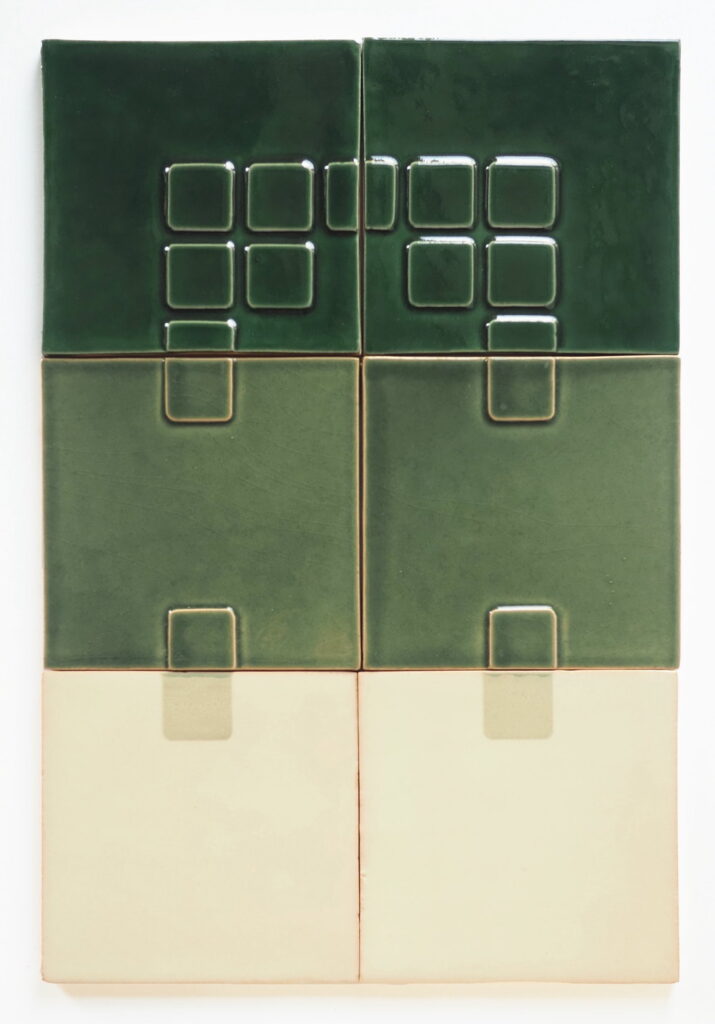 A two by three panel of Smink Studio tiles in dark green and cream, combining raised square Relief motifs with plain glazed tiles, arranged as wall panelling.