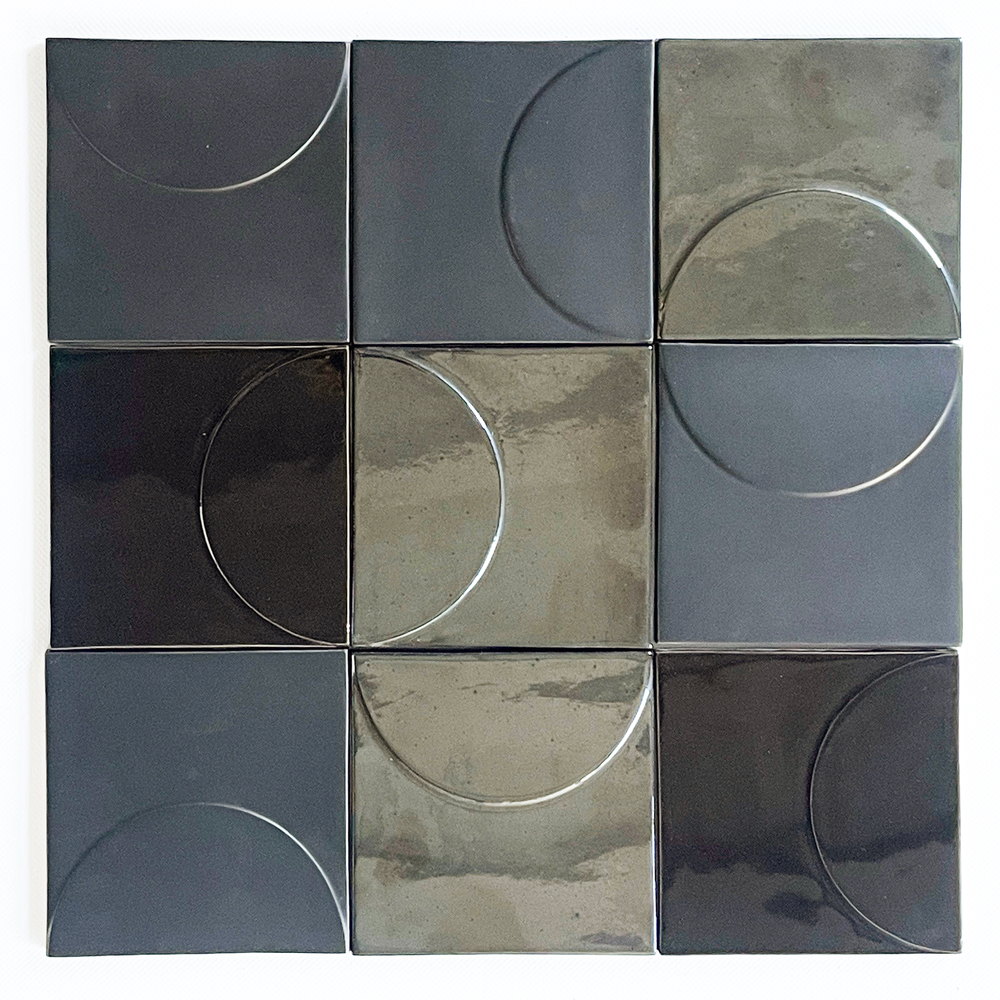 Nine Smink Studio Relief tiles in black, charcoal and grey glazes, each with a raised circle or half-circle catching the light.